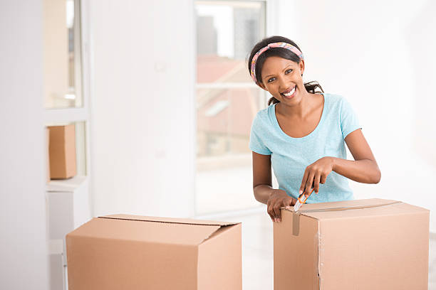 istock A woman smiling as she opens her box for moving house 473577826