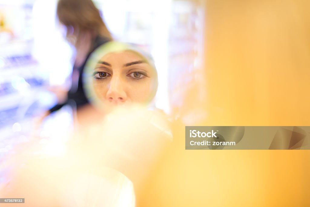 Vanity mirror Woman looking at  compact mirror to check lipstick color in shopping mall, copy space Aging Process Stock Photo