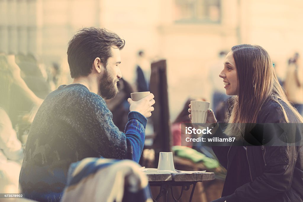 Hipster couple drinking coffee in Stockholm old town. Hipster couple drinking coffee in Stockholm old town. They're sitting face to face. The man is wearing a blue sweater and the woman a striped shirt with black leather jacket. Dating Stock Photo