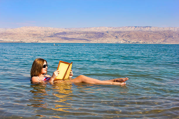 lee un libro niña flotando en el mar muerto en israel - dead sea fotografías e imágenes de stock