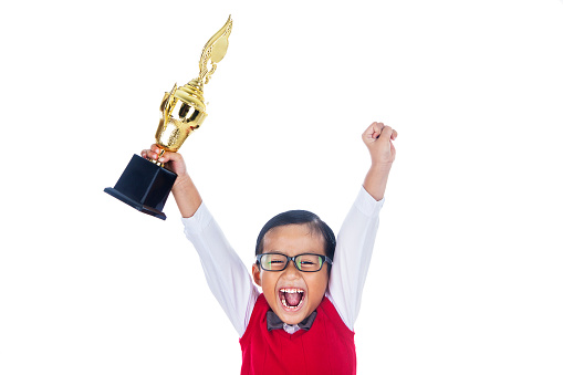 A young happy elementary student holding a trophy and celebrate his success. isolated on white