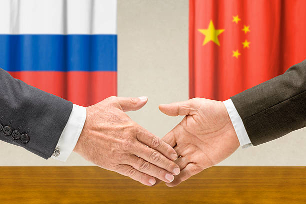 Representatives of Russia and China shake hands stock photo