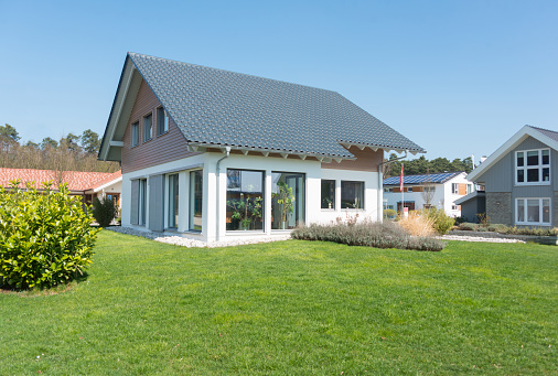 Tall green field of grass with pretty peach colored house far away in the background