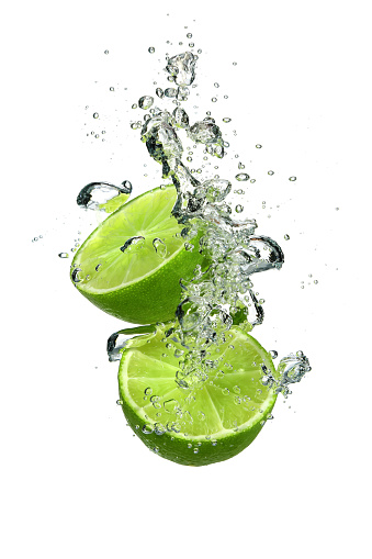 Two slices of lime falling into water on a white background in vertical composition