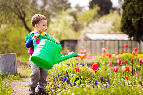 istock cute little boy watering flowers 473603796