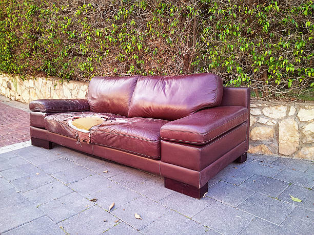 istock Old ragged leather sofa on a street 473606530