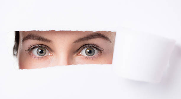 istock Women  eyes through a hole in a paper 473607296