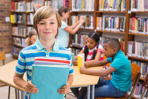 istock Cute pupil smiling at camera in library 473607556