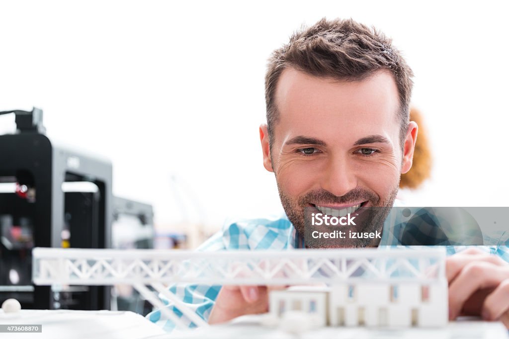 Man in 3D printer office watching printings Close up of an attractive architect sitting in a 3D printer office and watching 3D printings.  3D Printing Stock Photo
