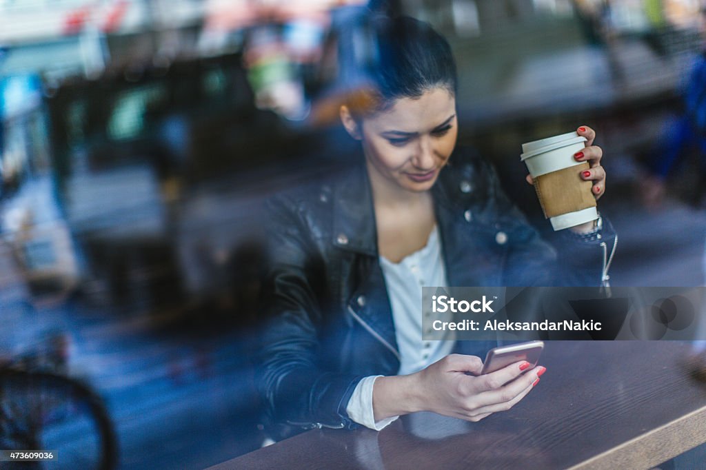 Morning coffee Photo of a beautiful woman sitting in a cafe, having a cup of coffee and using smartphone 20-29 Years Stock Photo