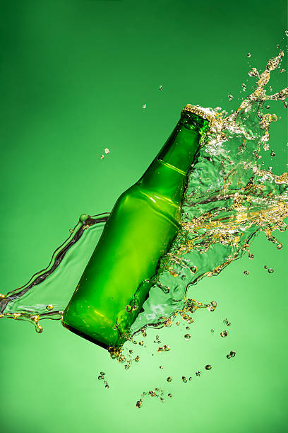 istock Bottle of beer with splash, on green background 473609264