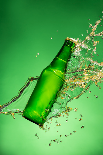 Bottle of beer with splash around on green background