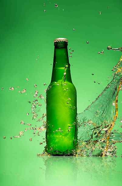istock Bottle of beer with splash, on green background 473609270