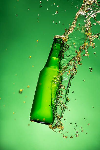 istock Bottle of beer with splash, on green background 473609276