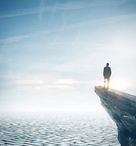 istock Businessman standing on a rock and looking at the sky 473612928