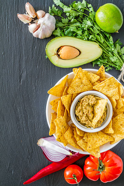 istock Guacamole sauce and ingredients, nacho chips in white bowl 473619752