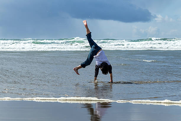 A boy does a cartwheel in the sand on the beach in Newport, Oregon.