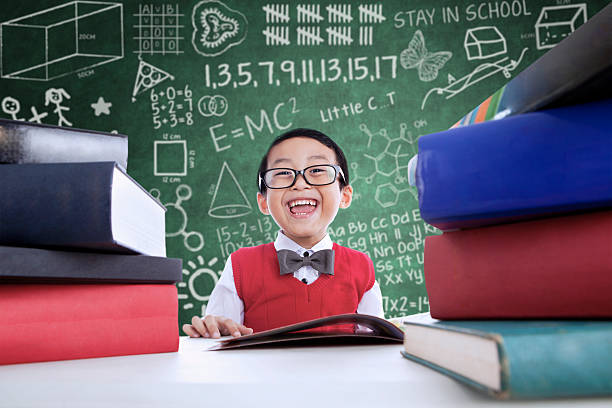 istock Asian boy laughing in class with stack of books 473634068