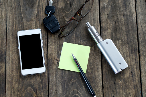 Men's Accessories , top view on a wooden background,  contains the phone , key, pen, glasses  and e-cigarette