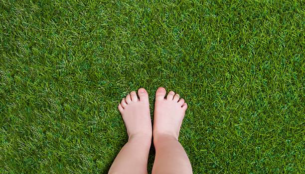 istock Baby legs standing  on green grass 473642282