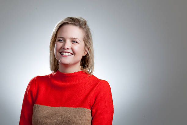 istock Young Pretty Blonde Laughing In Orange Sweater 473648794