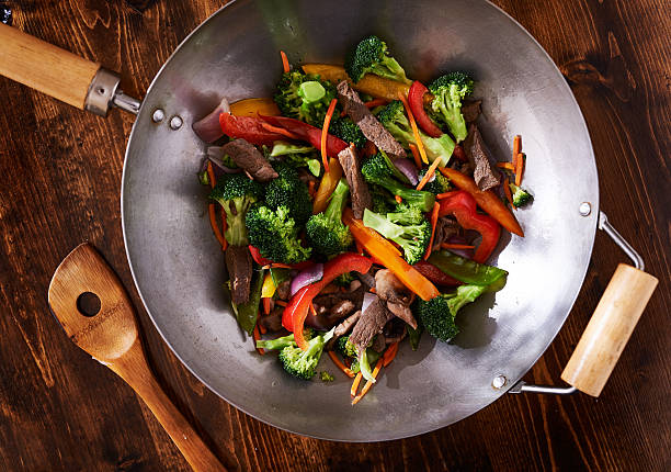 asian wok stir fry shot from over head asian wok stir fry shot from over head on top of wooden table top cooking pan overhead stock pictures, royalty-free photos & images