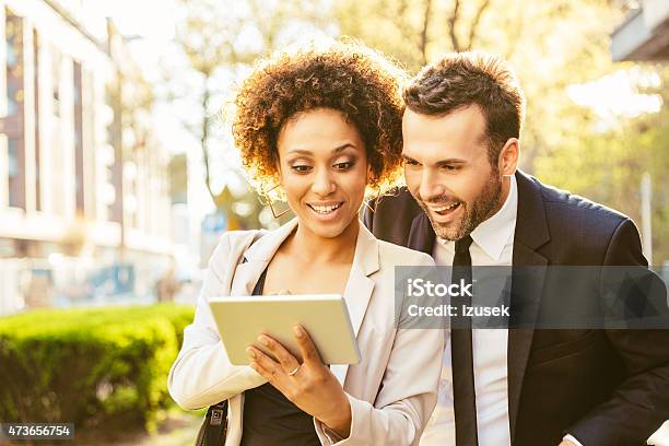 Two Business People Using Digital Tablet Outdoor At Sunset Stock Photo - Download Image Now