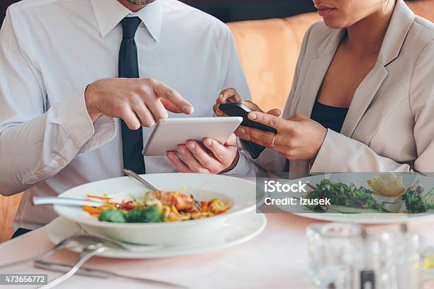 Business People Using Smart Phone And Digital Tablet At Lunch Stock Photo - Download Image Now