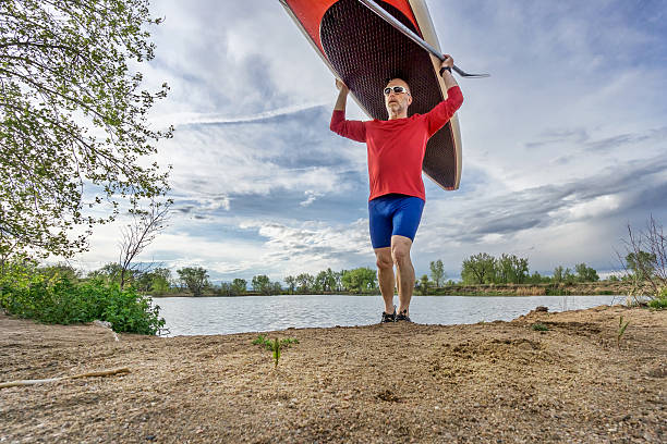 istock senior paddler carrying paddleboard 473659906