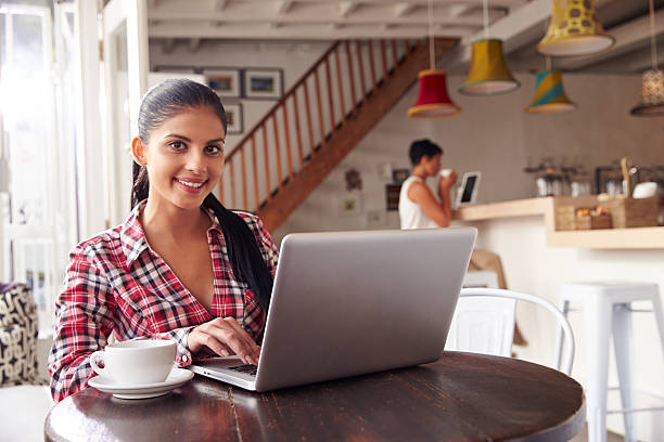 istock Young woman using laptop in a cafe Smiling To Camera 473668846