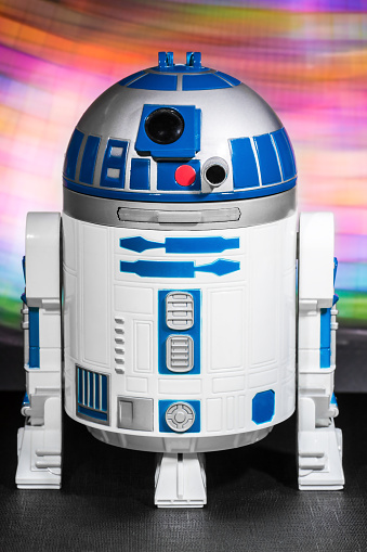 Paris, France - May 14, 2015: image of plastic figurine Lewis Galoob toys (1994), Micro Machines, interactive R2D2 toy robot, which has been shot on black textured table and colored light painting background. R2D2 is a fictional robot personnage, from the Star Wars saga films created by George Lucas in 1977 (LucasFilm ldt).