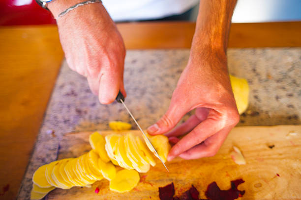 istock Young Slicing Russet Potatoes in Kitchen at Home 473675466