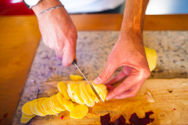 istock Young Slicing Russet Potatoes in Kitchen at Home 473675468