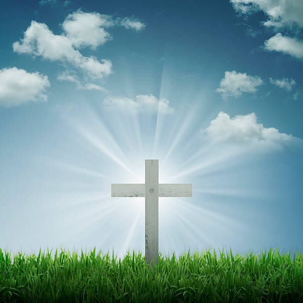 istock Focus on a white cross with sun rays and blue sky 473676406