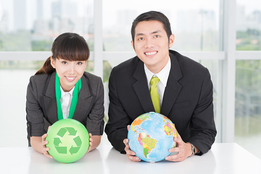 Image of businesspeople with a globe and a recycled circle in hands