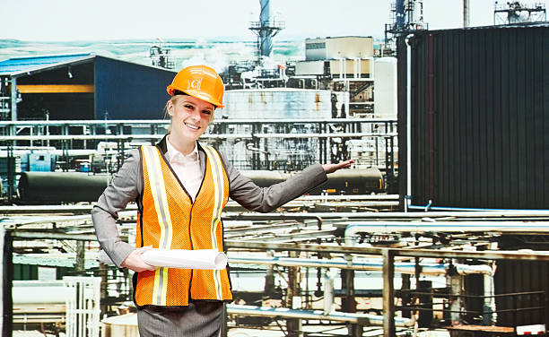 istock Smiling female architect presenting in oil refinery 473677342