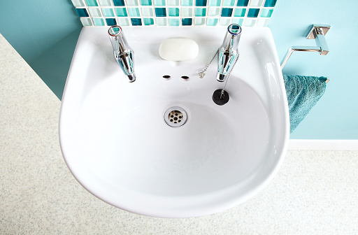 Top view of white sink with two tap and soap in contemporary home bathroom