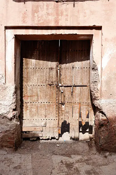 an ancient broken wooden maindoor on a pink wall