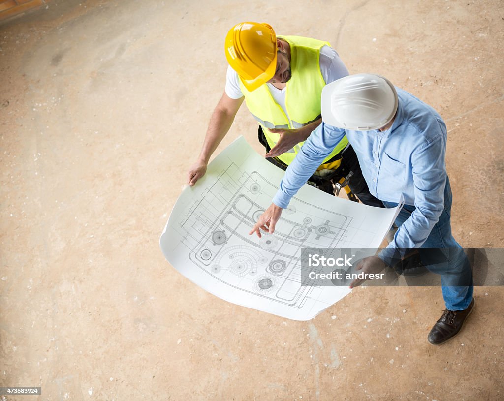 Construction workers looking at blueprints Construction workers looking at blueprints and working at a building site 2015 Stock Photo