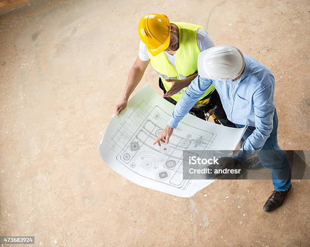 Construction Workers Looking At Blueprints Stock Photo - Download Image Now - 2015, Adult, Architect