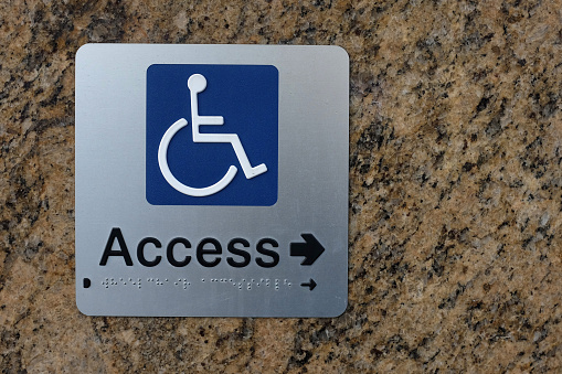 A disable access sign showing the direction to go for access into a building 
