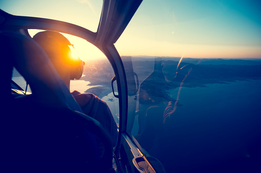 Flying in a helicopter over lake mead in Arizona. View is from behind with a view of  lake mead near the grand canyon. Time of ay is sunset or sunrise with a beautiful view and blue sky. Copy space on right. Can be flipped.