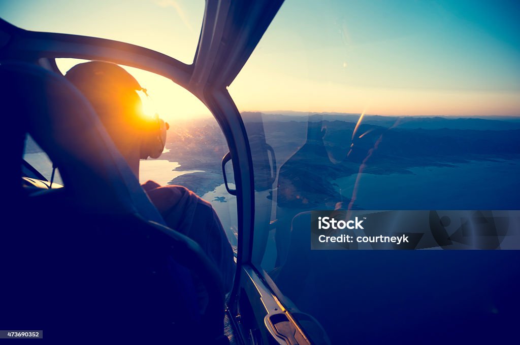 Flying in a helicopter over lake mead in Arizona. Flying in a helicopter over lake mead in Arizona. View is from behind with a view of  lake mead near the grand canyon. Time of ay is sunset or sunrise with a beautiful view and blue sky. Copy space on right. Can be flipped. Pilot Stock Photo