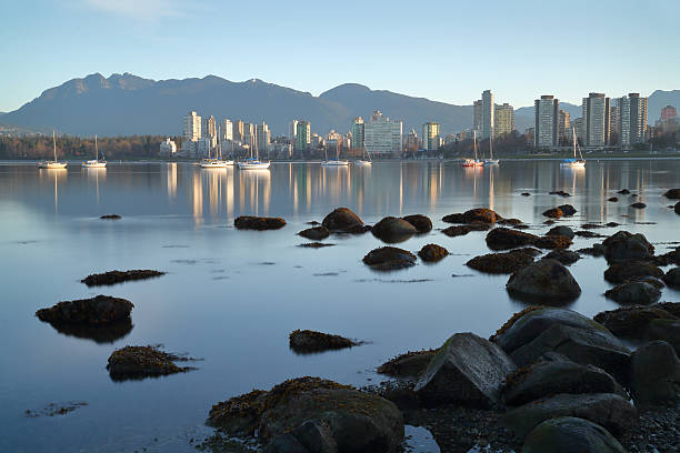 Vancouver Dawn, English Bay The view across English Bay, and anchored sailboats. Vancouver, British Columbia, Canada. beach english bay vancouver skyline stock pictures, royalty-free photos & images