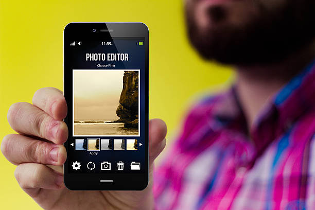 Hipster blog smartphone modern photography concept: Hipster with beard and checked shirt holding a smartphone with photo editor app on the screen photo editor photos stock pictures, royalty-free photos & images