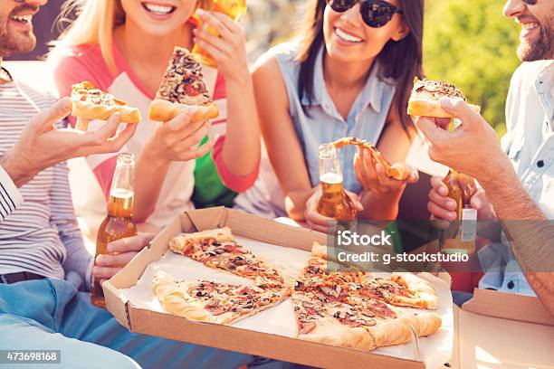 4 Friends With Drinks Sharing A Pizza Stock Photo - Download Image Now - 2015, Adult, Adults Only