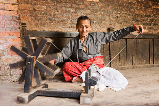 Nepali woman using spinning machine to make a wool. Bhaktapur. Kathmandu valley. Nepal.http://bem.2be.pl/IS/nepal_380.jpg