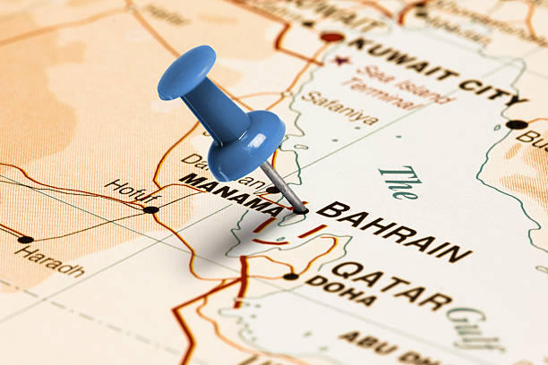 Series: Travel the world and visit major cities. Blue thumbtack (push pin) that is stuck in a map, which marks the city of Bahrain. The map is toned in pastel colors. Concept: Planning travel destinations or journey planning. Close-up view. Studio shot. Landscape orientation.