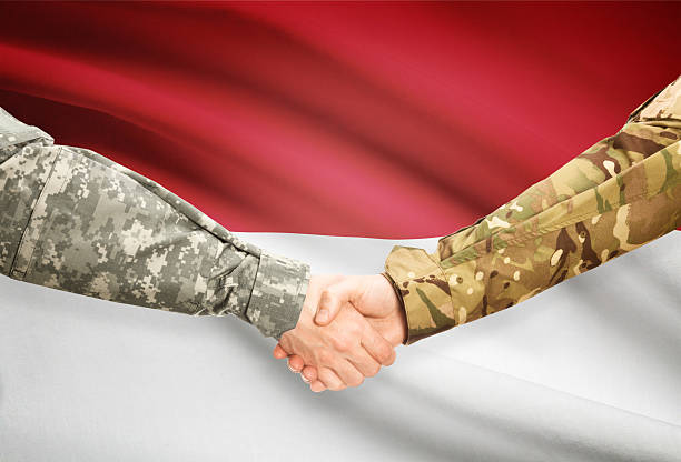 istock Men in uniform shaking hands with flag - Indonesia 473702190