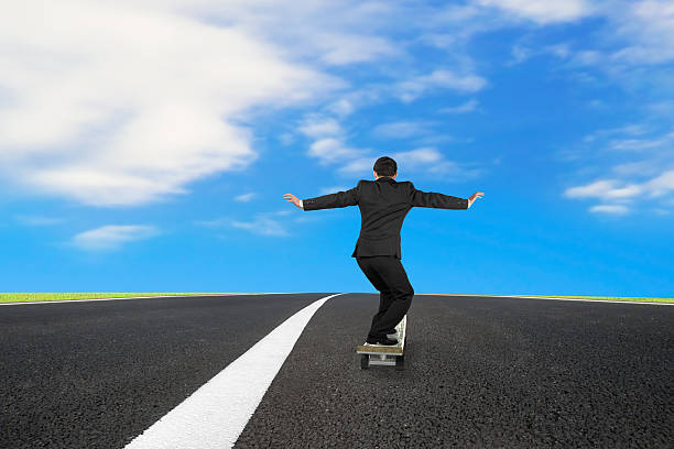 istock Businessman skateboarding on asphalt road with blue sky 473703822